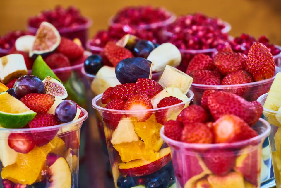 Cups of fresh fruit salad: strawberries, mango, blueberries and figs.