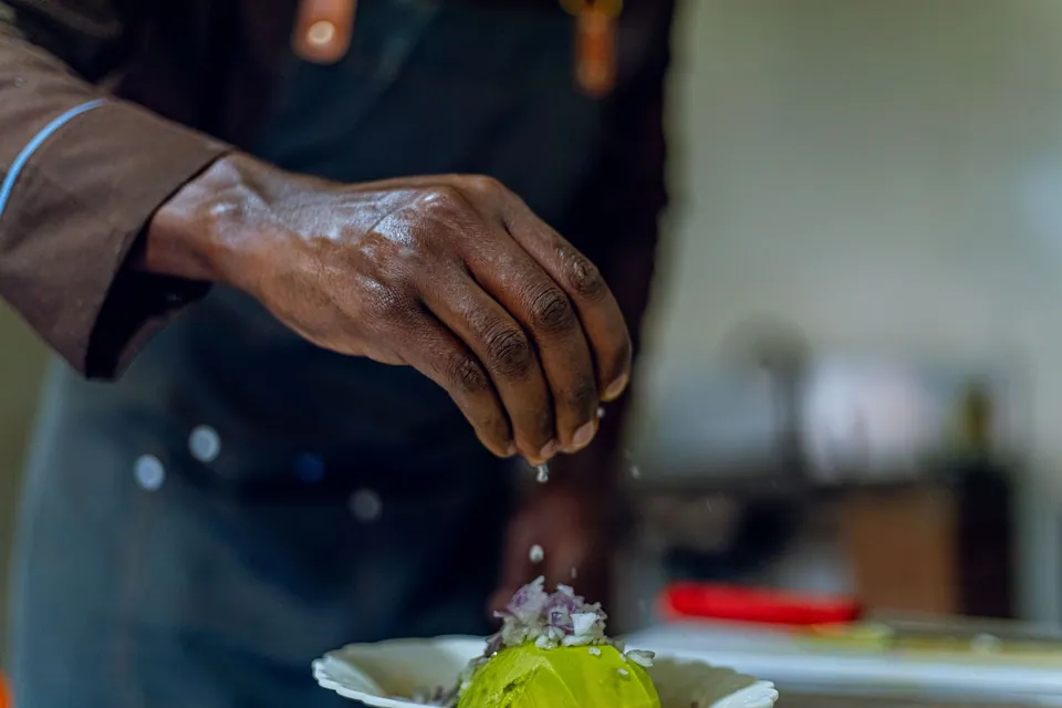 Main de chef terminant une assiette avec précision.