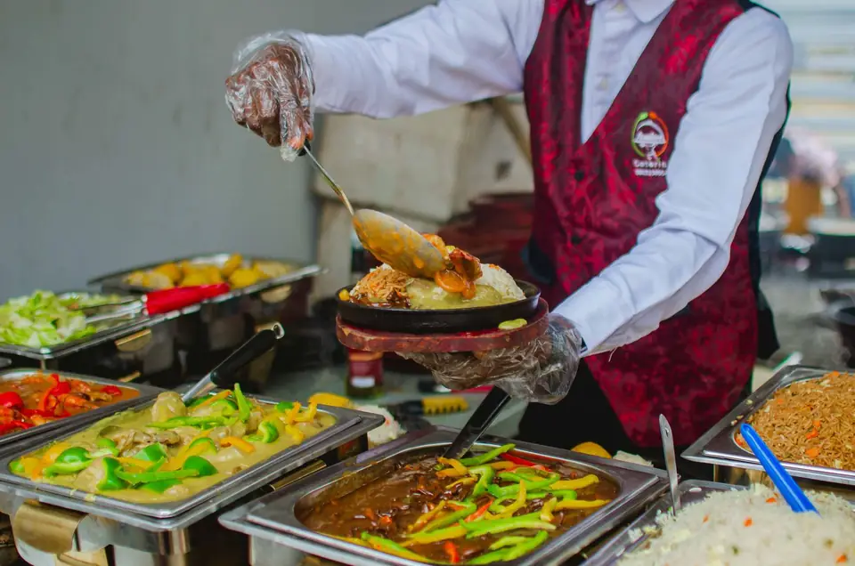 Chef serving from a buffet of hot dishes in chafing dishes.