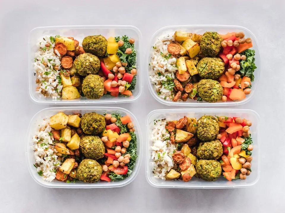 Four meal boxes: rice, vegetable balls, chickpeas and roasted vegetables.