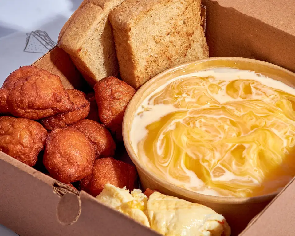 Takeaway box filled with akara, bread and pap.