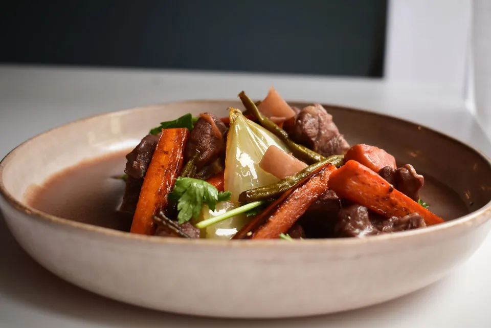 Beef stew with carrots and onions in a ceramic bowl.