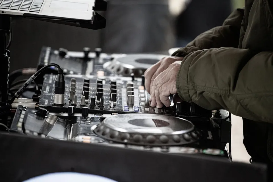 A DJ’s hands adjusting a mixer during a set.