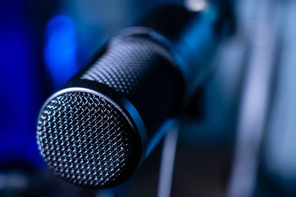 Close-up of a microphone grille against a blue background.