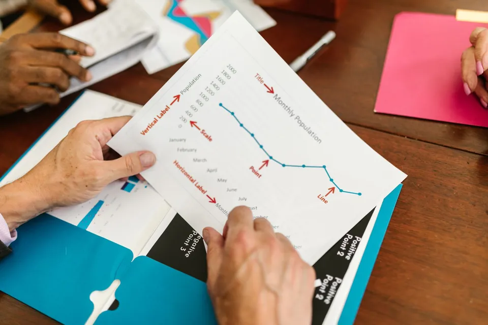 Hands holding a printed chart over a meeting table.
