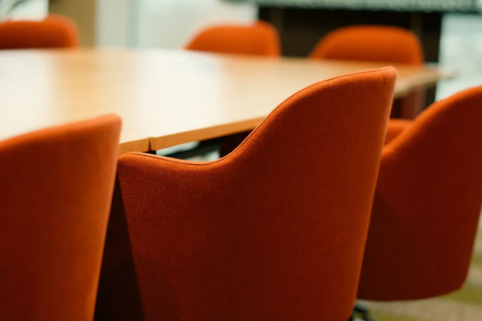 Orange armchairs around a wooden meeting table.