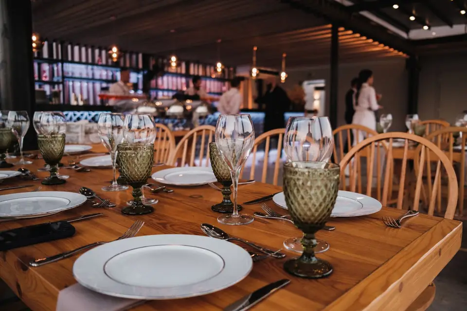 Restaurant table set with glasses and plates in warm light.