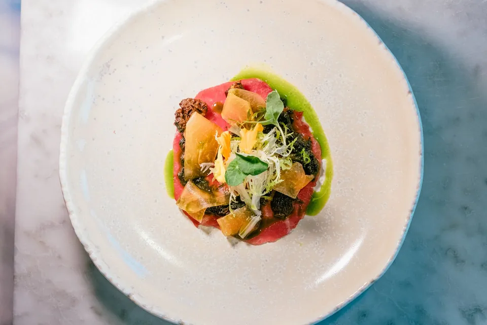 Colourful starter of crunchy vegetables and young shoots in a shallow bowl.