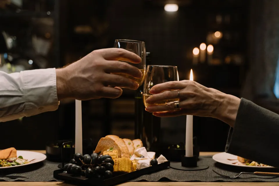 Two diners raising a toast by candlelight over a laid table.